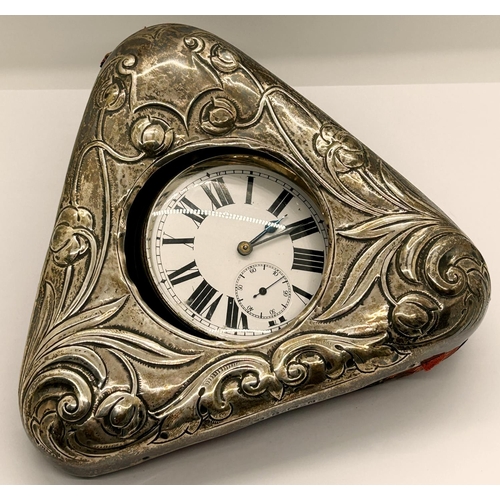 1384 - A heavy silver plated goliath bedside watch with enamelled dial set in a triangular shaped watch hol... 