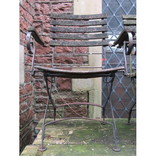 2011 - A weathered folding metal framed two seat garden bench with timber lathes and open scrolled arms, 12... 