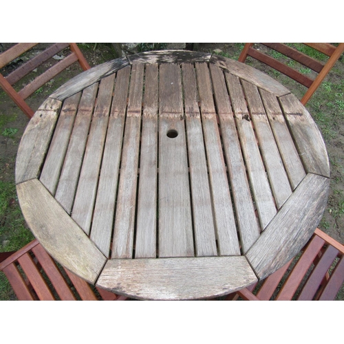 2049 - A weathered circular hardwood folding garden table with slatted top, 111cm diameter, together with f... 