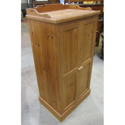 2182 - A stripped pine dwarf wardrobe, with shallow raised and shaped gallery over a pair of full length re... 