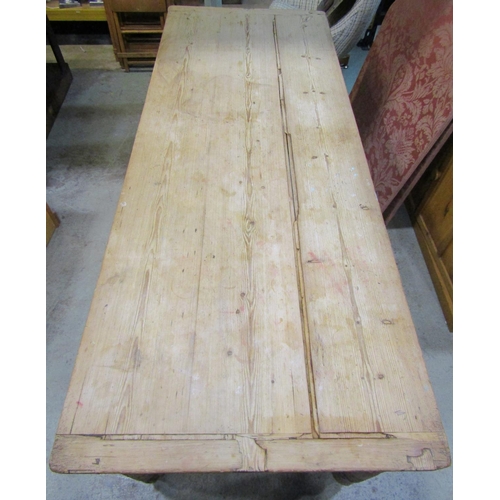 2198 - A stripped pine farmhouse kitchen table, the rectangular rustic boarded top raised on four turned an... 