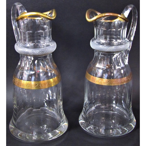 1132 - A pair of elegant cut glass water jugs with gilded rim and hatched engraved collar, 29 cm high.