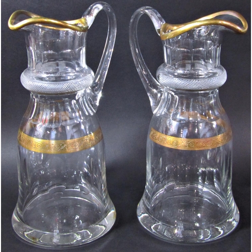 1132 - A pair of elegant cut glass water jugs with gilded rim and hatched engraved collar, 29 cm high.