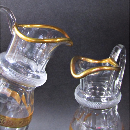 1132 - A pair of elegant cut glass water jugs with gilded rim and hatched engraved collar, 29 cm high.