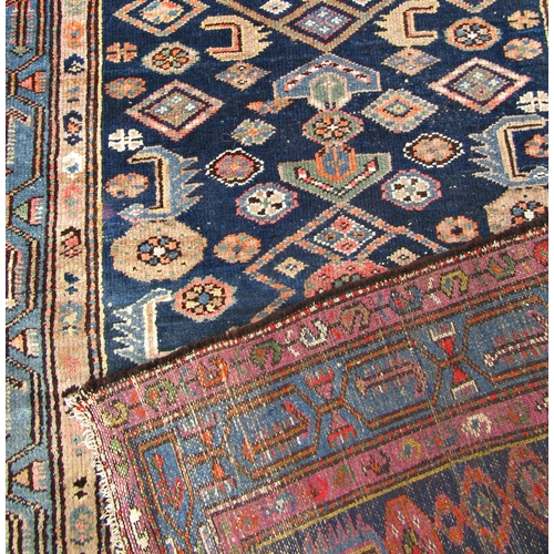 1668 - An old Malayer carpet with a repeating geometric pattern on a blue ground