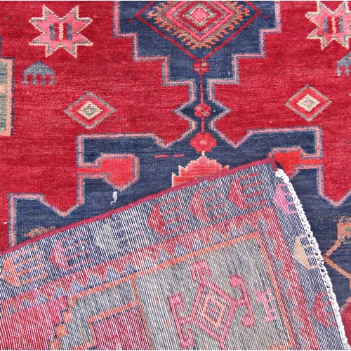 1681 - A slightly worn Kazak carpet with three stepped interlocking lozenges, on a red ground.  188cm x 118... 