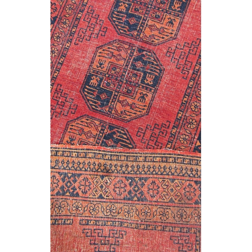 1686 - A faded and worn old Turkoman runner with a row of ten central elephant foot guls on an orange groun... 