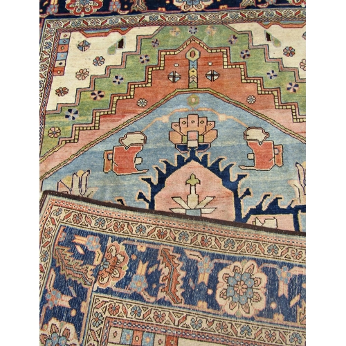 1688 - A Heriz carpet with a broad blue flower shaped central medallion on a pale cream ground, signed in a... 