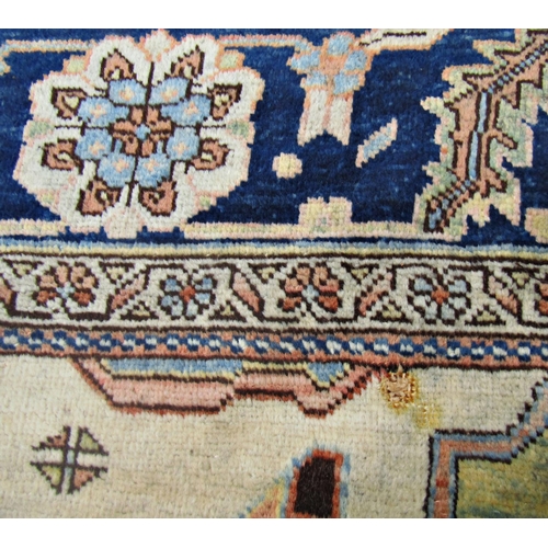 1688 - A Heriz carpet with a broad blue flower shaped central medallion on a pale cream ground, signed in a... 