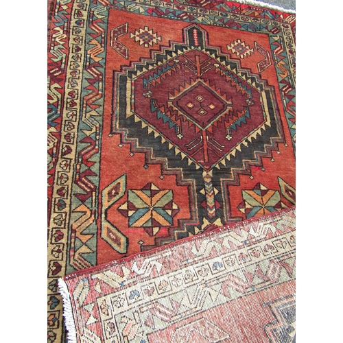 1692 - A Kazak design carpet with two interlocking stepped medallions on a madder field, 211cm x 128cm