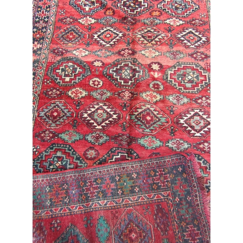 1696 - A Bokhara style carpet with an all over geometric hexagonal pattern on a red ground, 290cm x 152cm