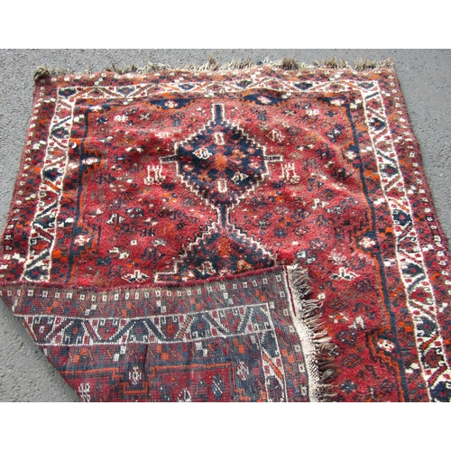 1702 - A Middle Eastern carpet with triple linked lozenge on a red ground, 190cm x 140cm approx.