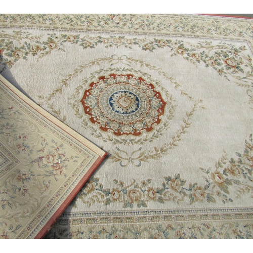 1707 - A machine made carpet of European design with a floral central and trailing flowers on a cream groun... 