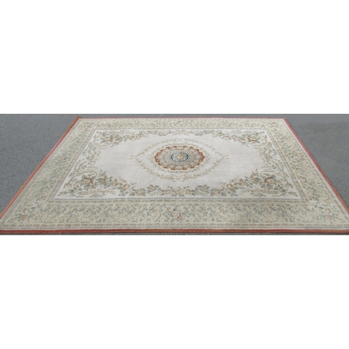 1707 - A machine made carpet of European design with a floral central and trailing flowers on a cream groun... 