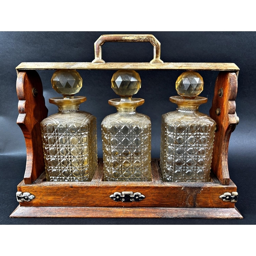 1172 - A Daniel & Arter oak three bottle tantalus with nickel silver mounts and two port labels. (Locked an... 