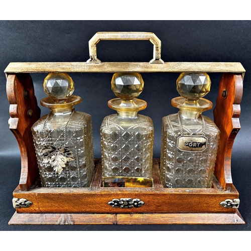 1172 - A Daniel & Arter oak three bottle tantalus with nickel silver mounts and two port labels. (Locked an... 