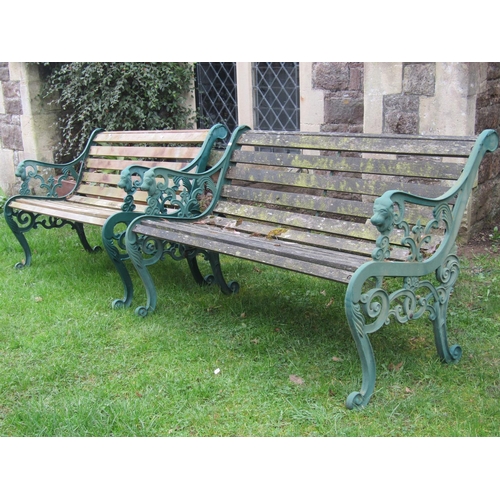 2054A - A pair of two seat garden benches with weathered timber lathes raised on decorative pierced and scro... 