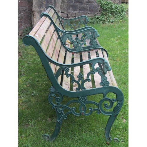 2054A - A pair of two seat garden benches with weathered timber lathes raised on decorative pierced and scro... 