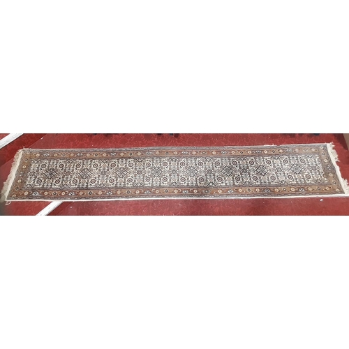 1713 - A narrow Middle Eastern runner with a repeating pattern in pale blues and brown, 330cm x 56cm approx... 