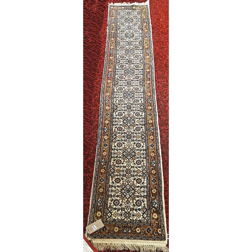 1713 - A narrow Middle Eastern runner with a repeating pattern in pale blues and brown, 330cm x 56cm approx... 