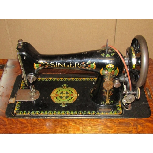 2097 - A vintage oak cased floorstanding but portable Singer sewing machine with decorative printed detail,... 