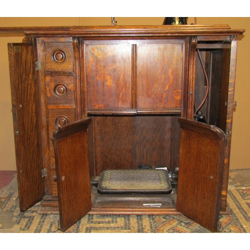 2097 - A vintage oak cased floorstanding but portable Singer sewing machine with decorative printed detail,... 