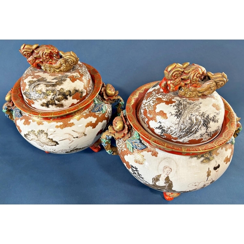 1039 - A pair of large Satsuma lidded urns standing on three legs, decorated with panels of characters, bir... 