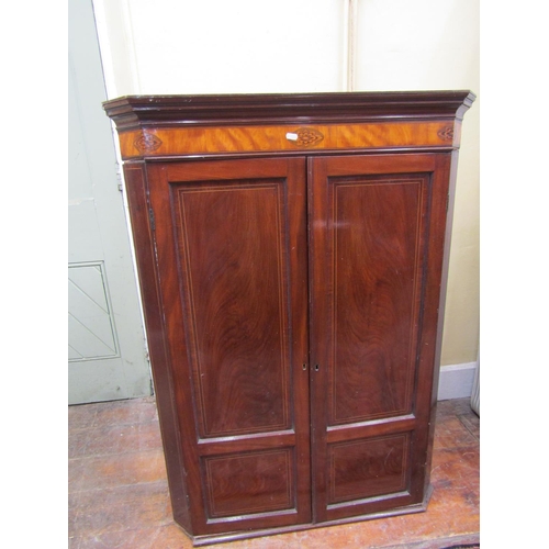 2588 - A Georgian mahogany hanging corner cupboard enclosed by a pair of panelled doors enclosing four shap... 