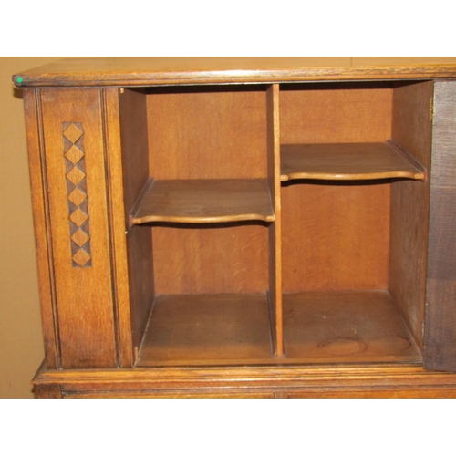 2163 - An early 20th century oak freestanding side cupboard enclosed by a central panelled door, with shelv... 