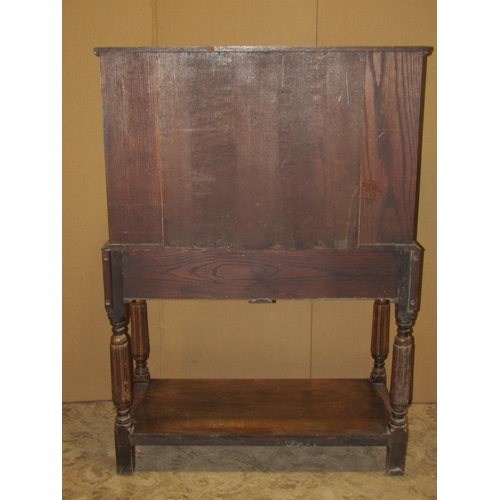 2163 - An early 20th century oak freestanding side cupboard enclosed by a central panelled door, with shelv... 