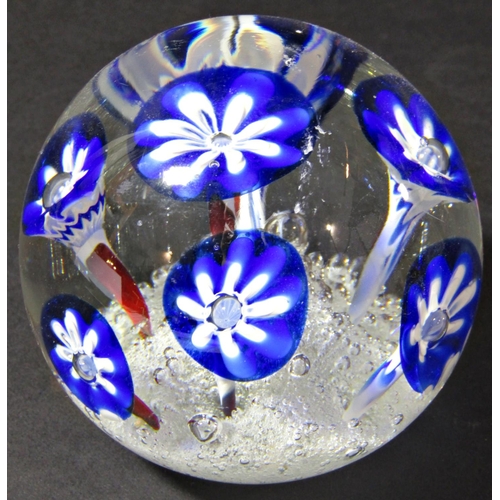 1181 - A single clear glass paperweight with seven stylised blue flowers emerging from a frothy, bubbly exp... 