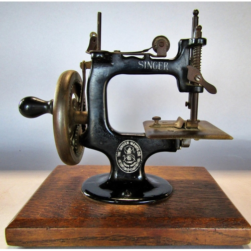 1452 - A miniature Singer Sewing Machine, on a wooden plinth, 20cm high x 19cm wide (inc the plinth)