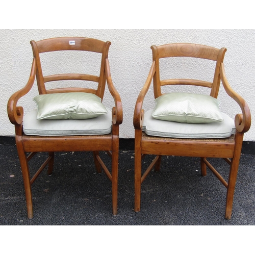 2664 - A pair of continental elbow chairs in chestnut with scrolled arms, sabre legs and rush work seats