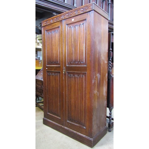 2197 - 1920s oak wardrobe enclosed by a pair of full  length linen fold panelled doors beneath a carved fri... 