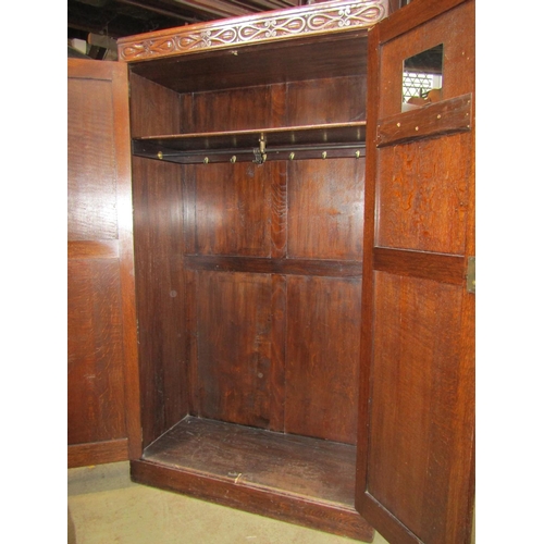 2197 - 1920s oak wardrobe enclosed by a pair of full  length linen fold panelled doors beneath a carved fri... 