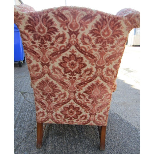 2431 - A Georgian style wing chair with scrolled arms and loose cushion, raised on a timber frame work