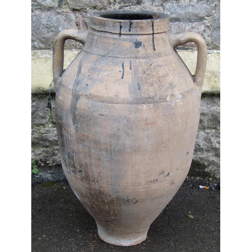 2064 - An old weathered terracotta jar with moulded loop handles and incised banded detail, 63cm high