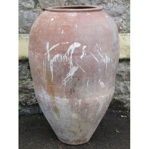 2069 - An old weathered terracotta oviform and tapered jar with ring neck, 65cm high