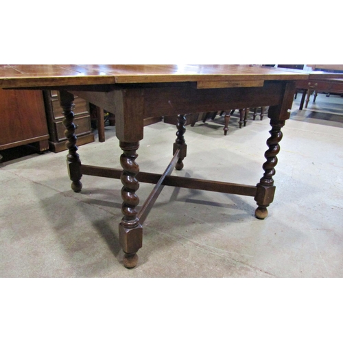 2234 - A 1920s oak drawleaf dining table raised on barley twist supports united by a moulded X framed stret... 