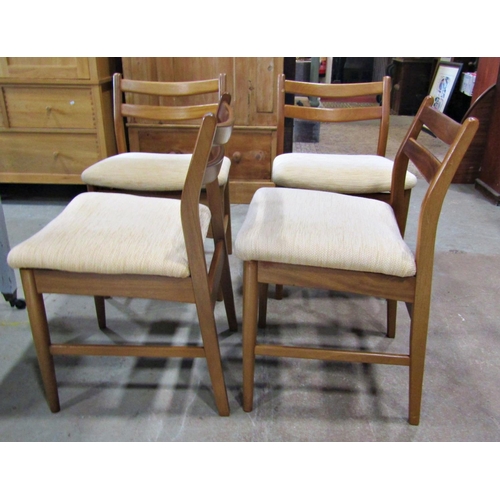 2243 - Set of four 20th century teak dining chairs with low bar backs over upholstered seats raised on simp... 