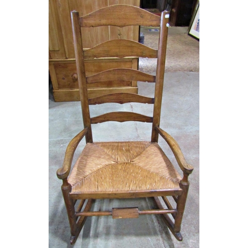 2245 - An arts and crafts style countrymade low ladder back rocking armchair with rush seat