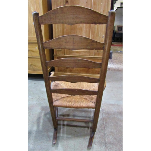 2245 - An arts and crafts style countrymade low ladder back rocking armchair with rush seat