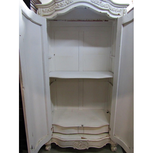 2335 - An Armoire with cream painted and distressed finish, the serpentine front enclosed by a pair of full... 