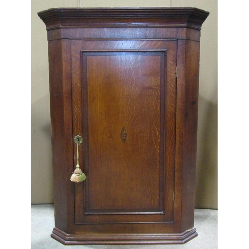 2391 - A Georgian oak hanging corner cupboard enclosed by a rectangular moulded and crossbanded rectangular... 