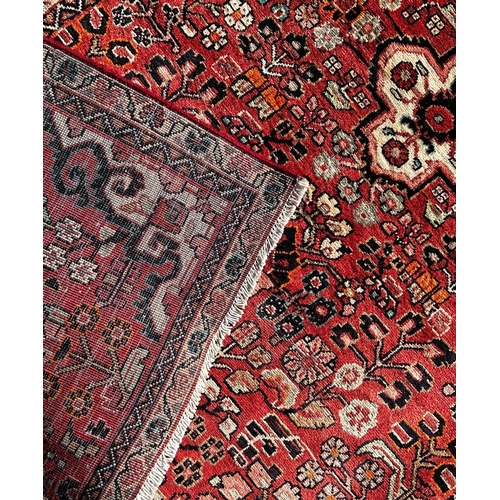 1612 - North West Persian Sarouk rug, with an all over stylised floral pattern on a madder red ground,188cm... 