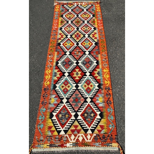 1615 - A Chobi Kilim Runner with a central panel of diamond medallions defined in black borders, 252cm x 82... 