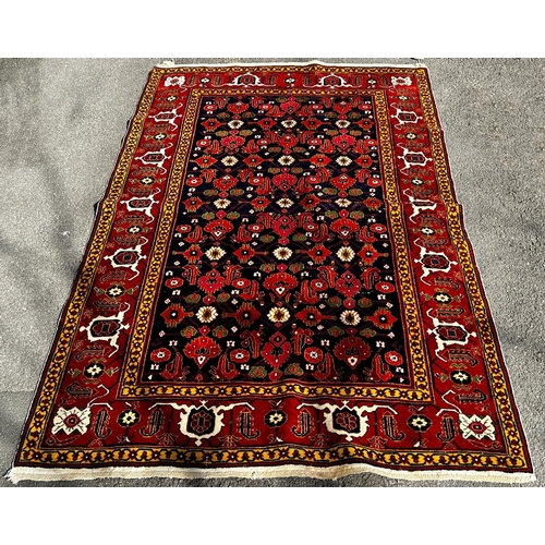 1622 - A fine brightly coloured Shirvan carpet with a central panel geometric stylised flowers on a dark bl... 