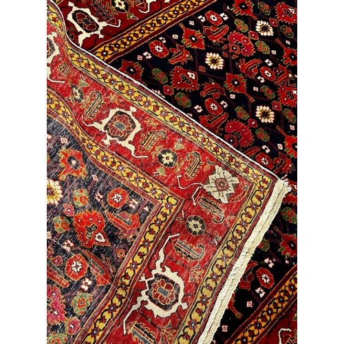 1622 - A fine brightly coloured Shirvan carpet with a central panel geometric stylised flowers on a dark bl... 