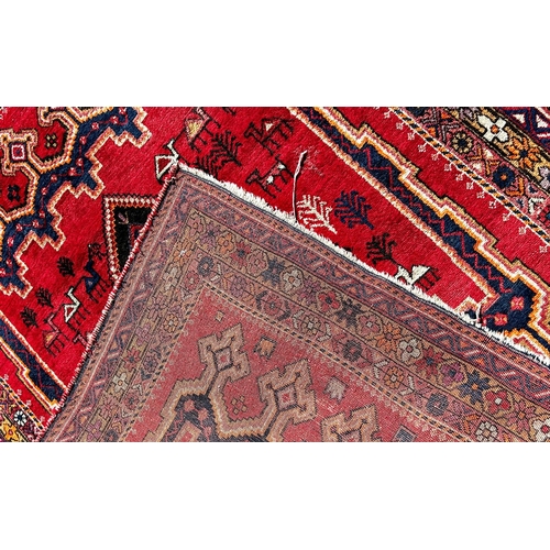 1634 - A Middle Eastern Gabbeh style carpet with a central medallion on a red ground interspersed with styl... 