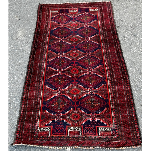 1653 - A Kazak carpet with repeating stepped medallions in reds and blues, 172cm x 92cm approx.